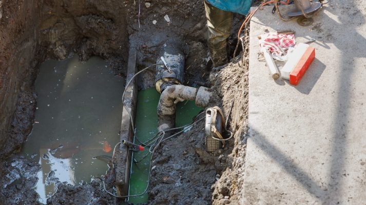 Utility worker fixing broken water main, top view